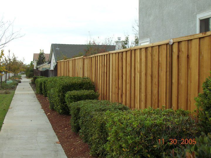 A wooden fence along a sidewalk next to a house.
