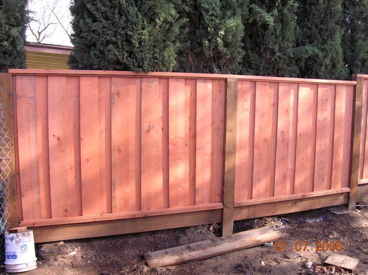 A wooden fence is being built next to a chain link fence.