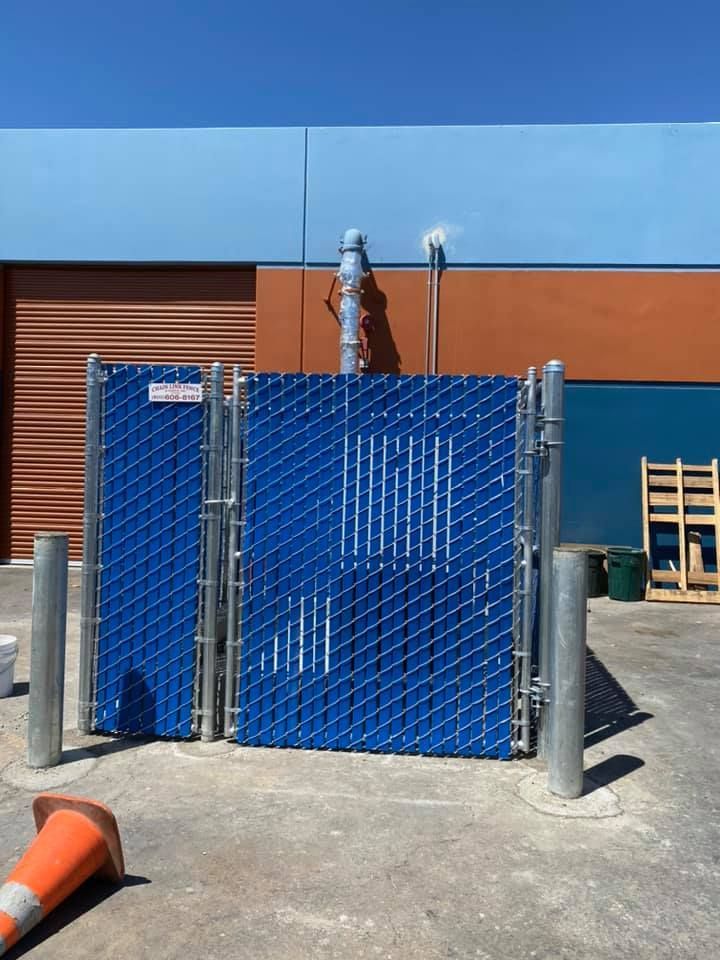 A blue chain link fence is in front of a building
