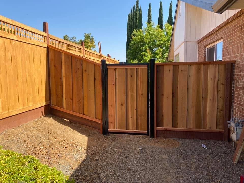 A wooden fence with a gate in the backyard of a house.