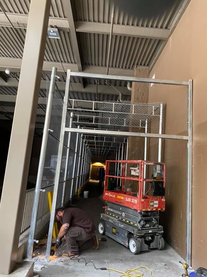 A man is kneeling next to a scissor lift in a building.
