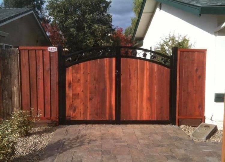 A wooden gate with a black frame is in front of a house