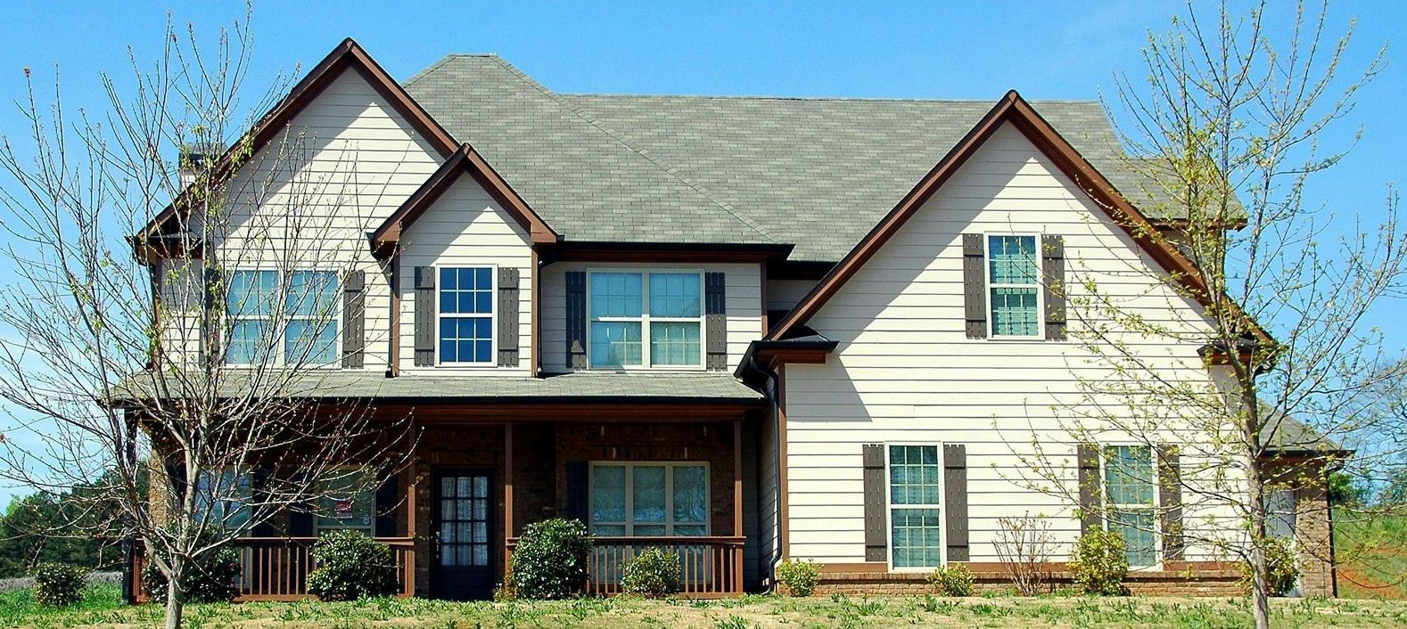 A large house with a porch and a blue sky in the background