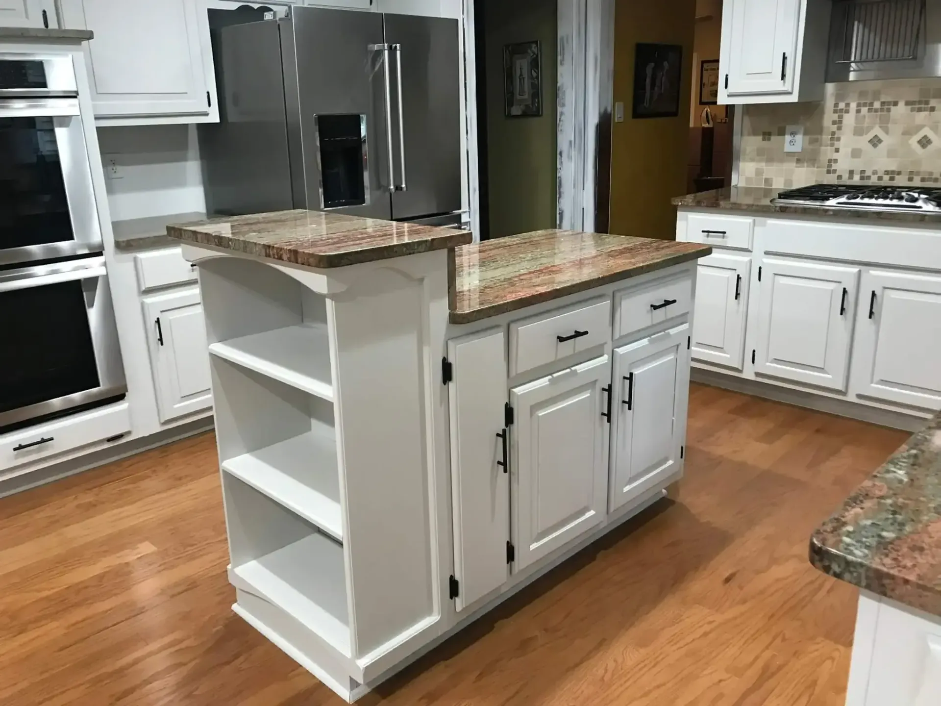 A kitchen with white cabinets , granite counter tops , and stainless steel appliances.