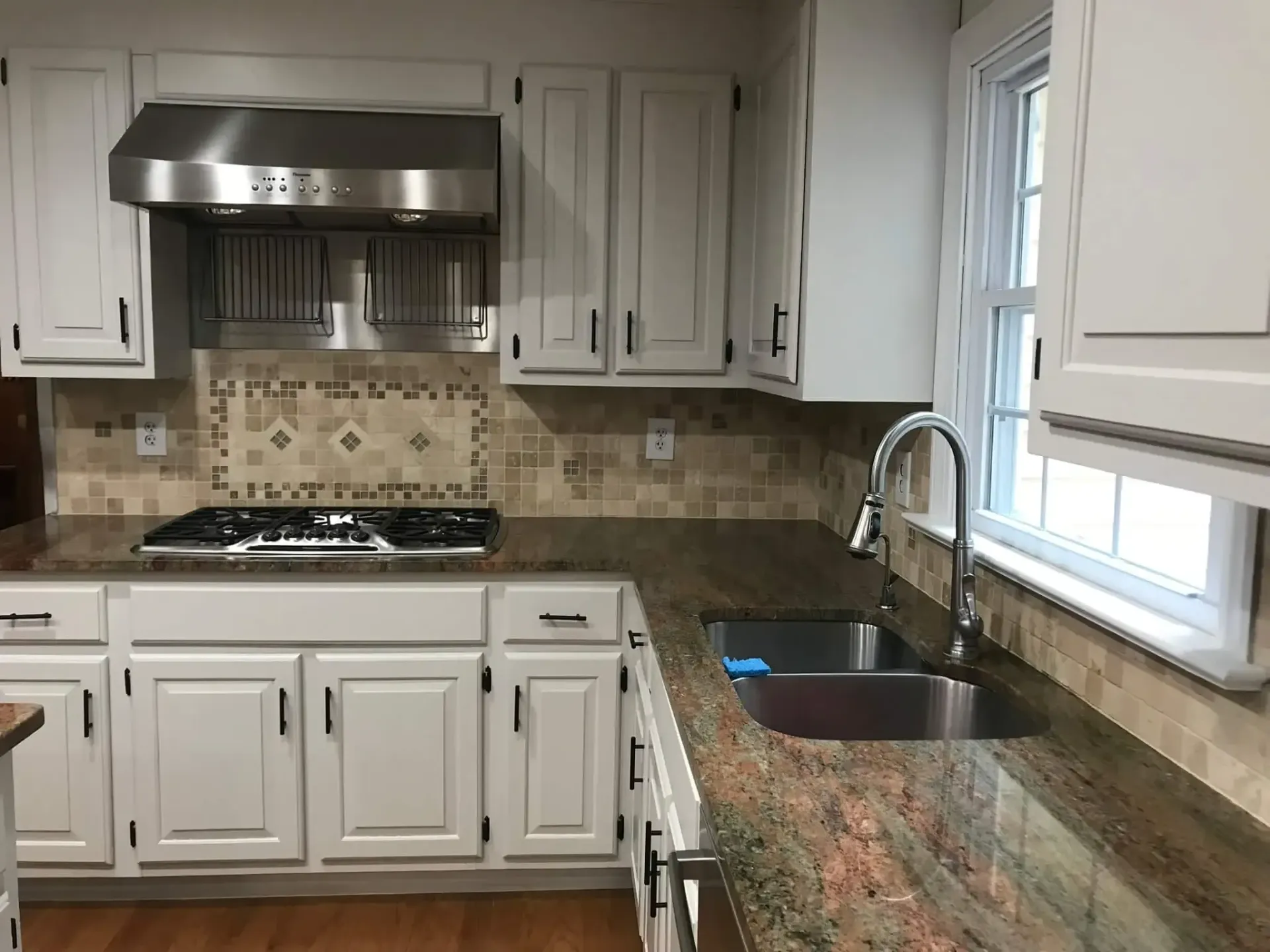 A kitchen with granite counter tops and white cabinets