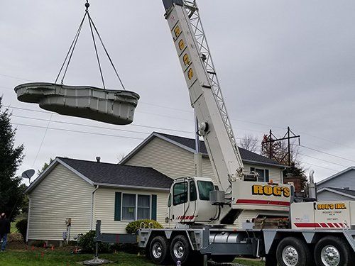 A crane is lifting a pool into a house.