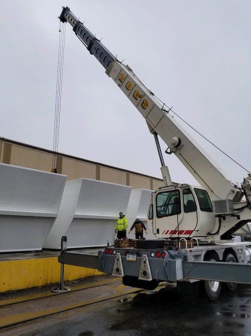 A large crane is lifting a large piece of metal.
