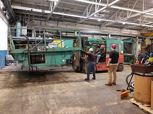 A group of men are working on a machine in a factory.