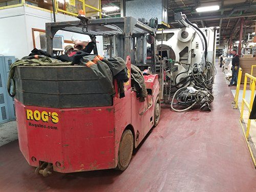 A red forklift is parked in a warehouse next to a machine.