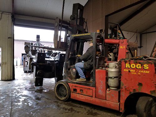 A man is driving a red forklift in a garage.