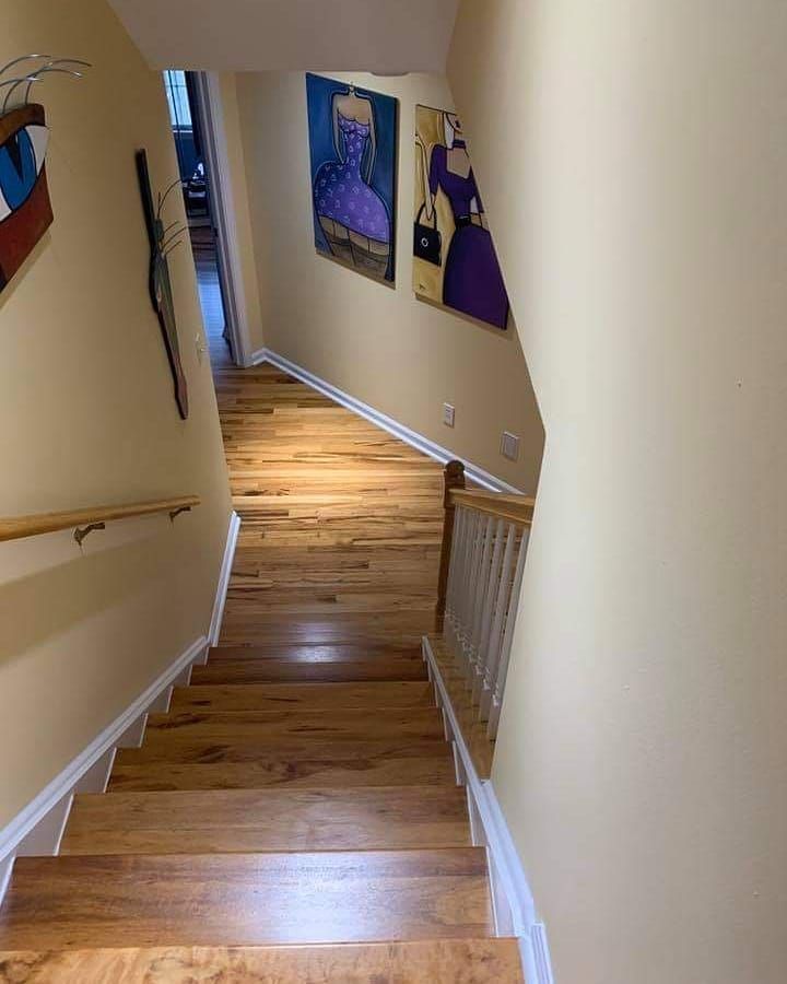 Wooden staircase leading downward with art on walls.