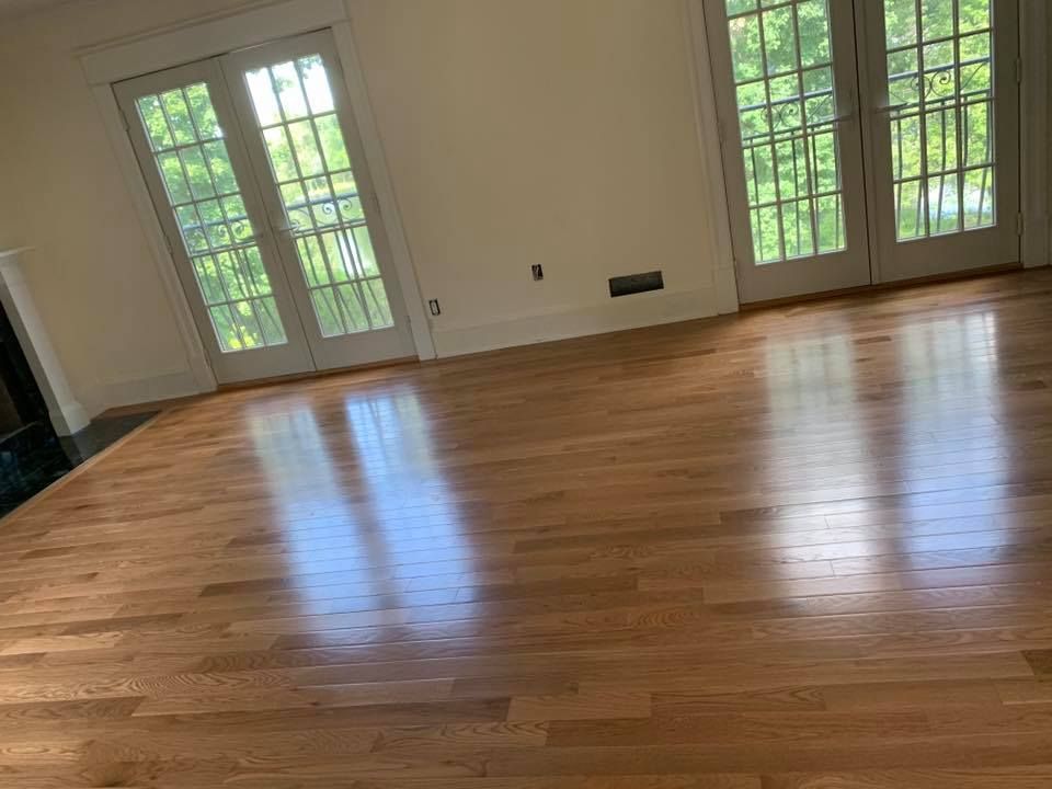 Hardwood floors in a room with light-colored walls and French doors, reflecting sunlight.