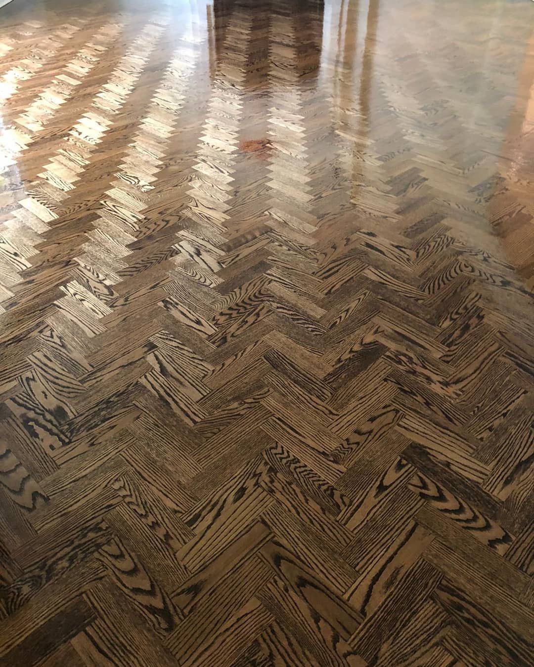 Herringbone pattern wooden floor reflecting natural light.