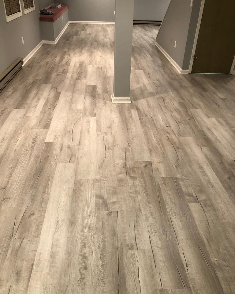 Herringbone wood floor, stained in shades of brown, reflecting light.