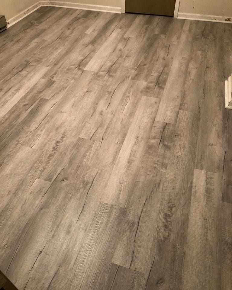Gray, wood-look flooring installed in a room. Boards vary in shade and have wood grain details.
