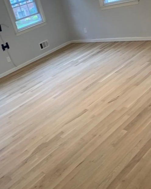 Light wood floor in a room with gray walls and a window.