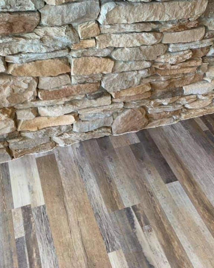 Stone wall meets wood-look flooring; neutral tones of brown and tan dominate the scene.