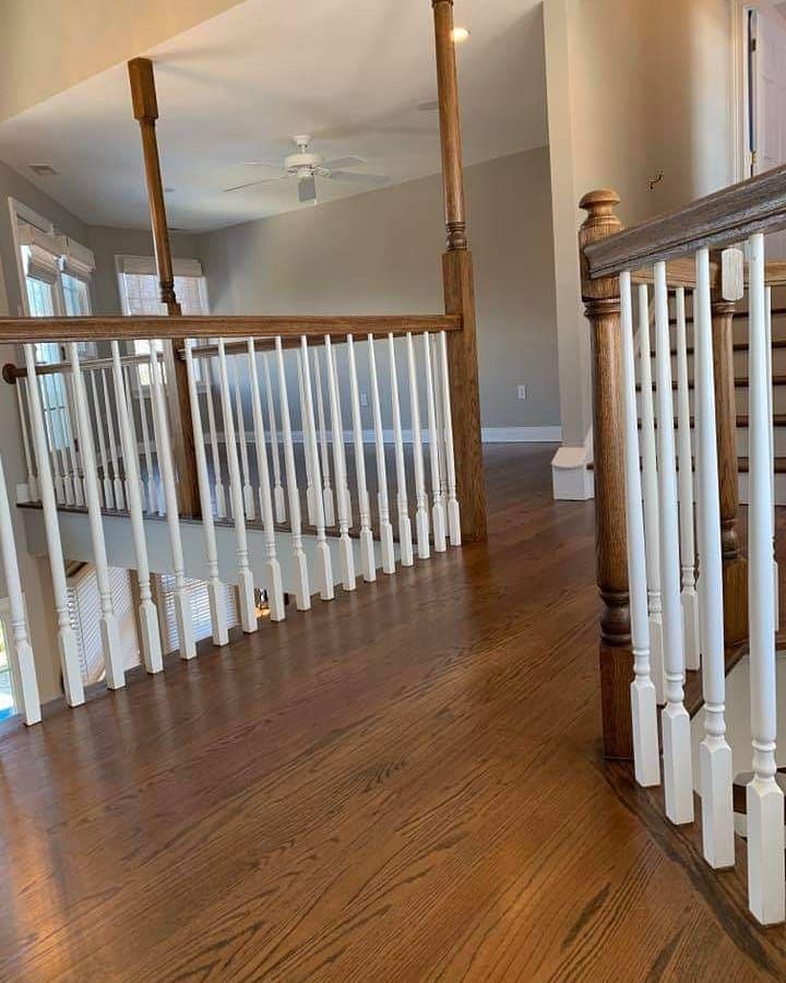 Wooden staircase with white spindles, brown railings, and hardwood floors.