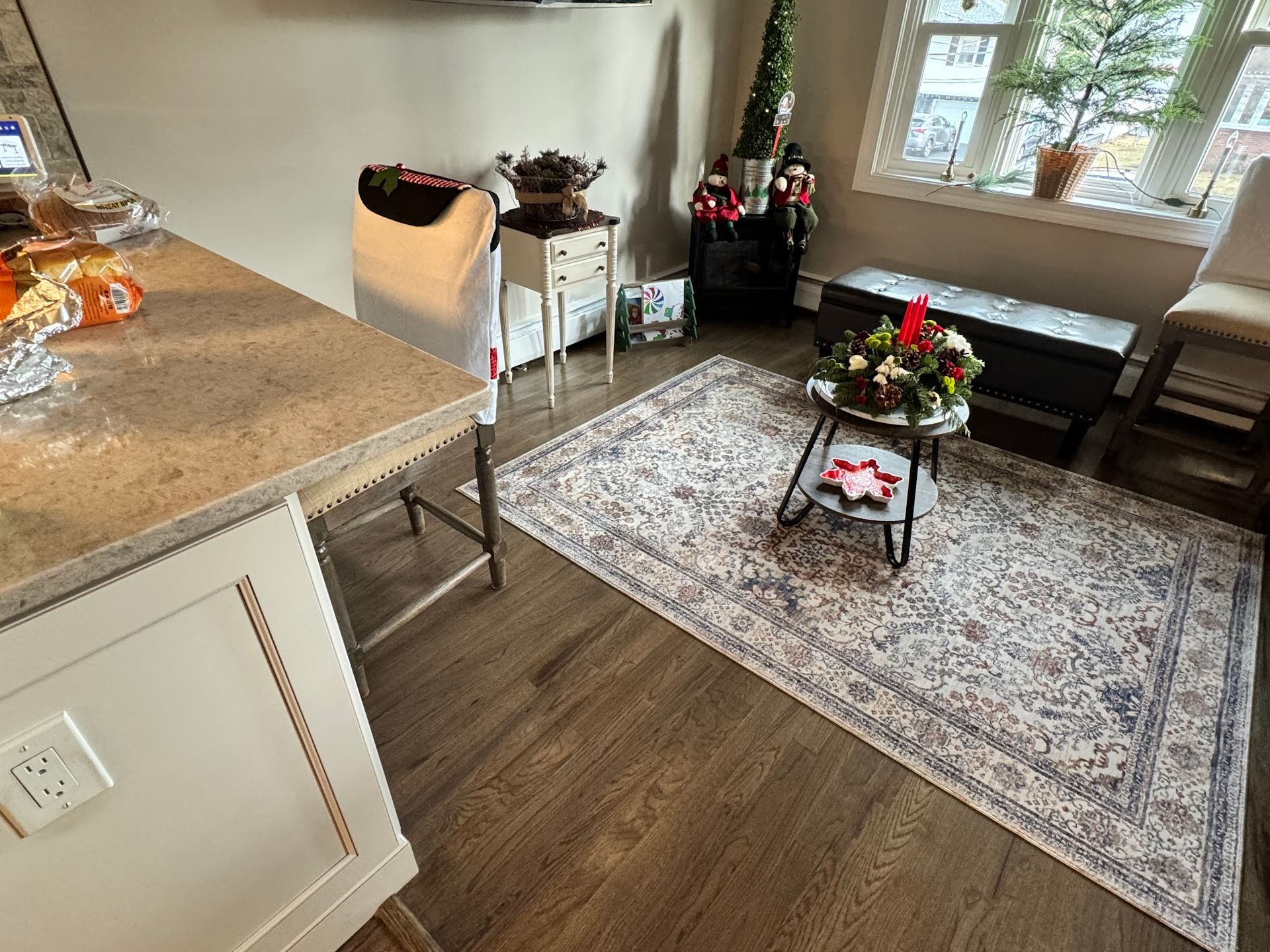 A cozy room with a rug, small table with decorations, and a kitchen island with a countertop.