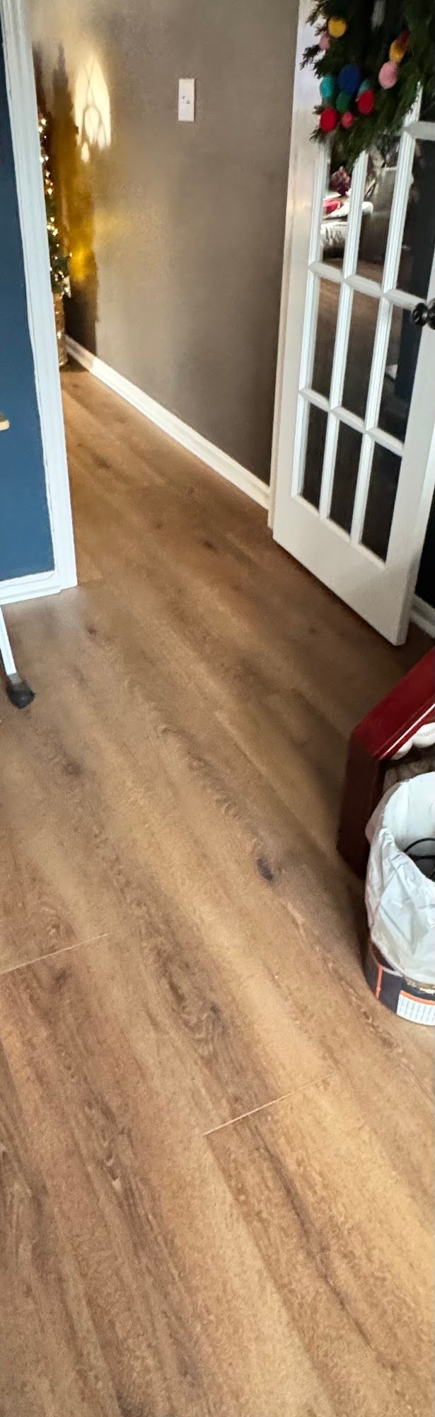 Wooden floor in a room with a white door, blue wall, and dark gray wall.