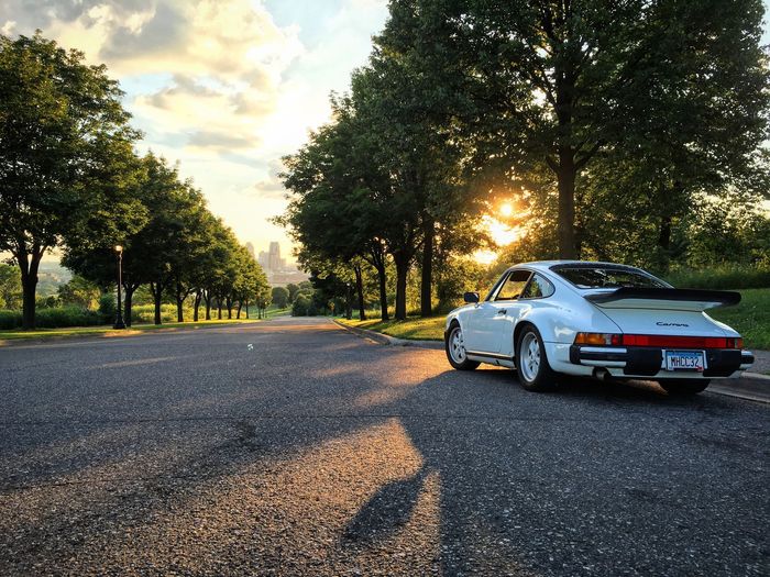 White Porsche 911 Parked on a Tree-Lined Road at Sunset | Norgren's Auto Center