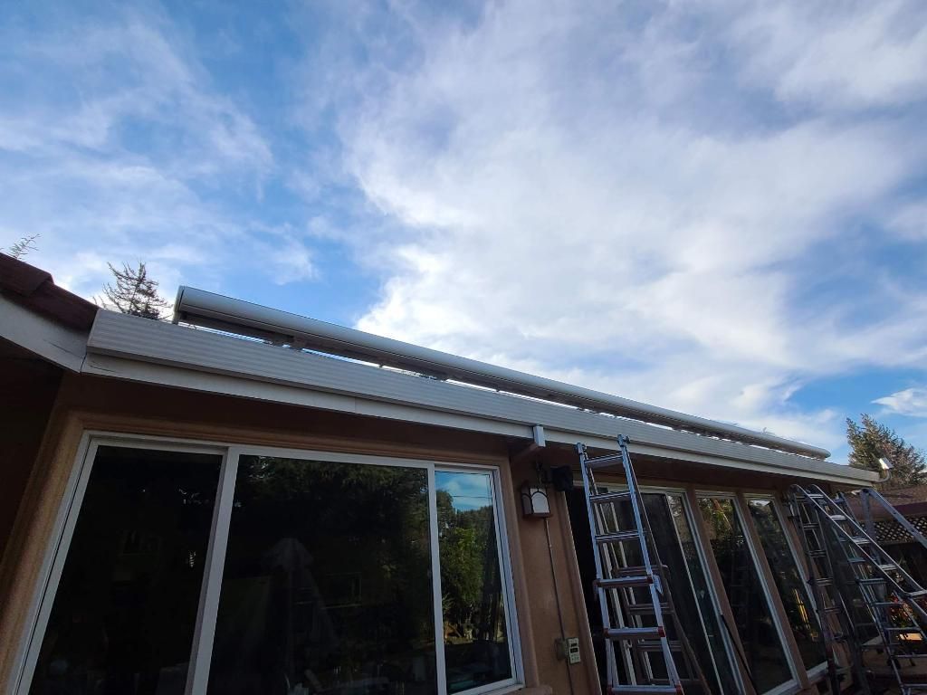 A house with a ladder on the side of it and a blue sky in the background