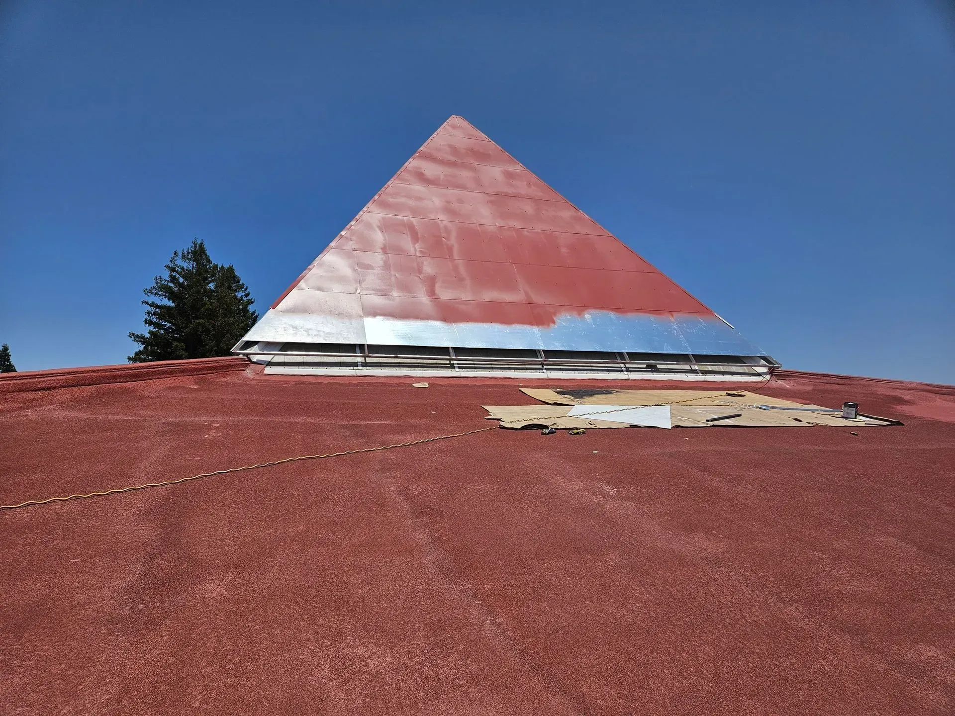 A pergola with a screen on the side of it in a backyard.