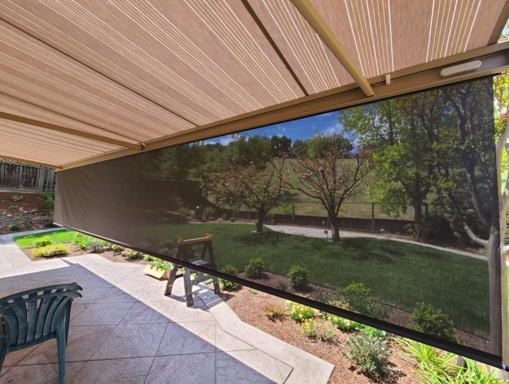 A patio with a canopy over it and a view of a park.