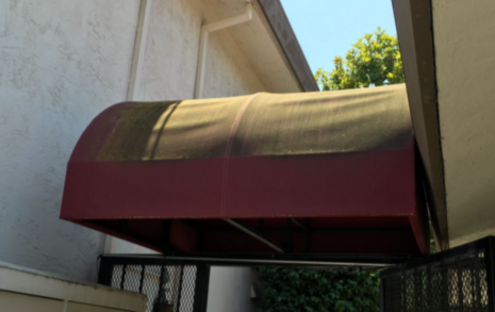 A red awning is hanging from the side of a building