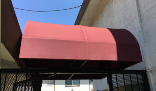 A red awning is hanging over a fence in front of a building