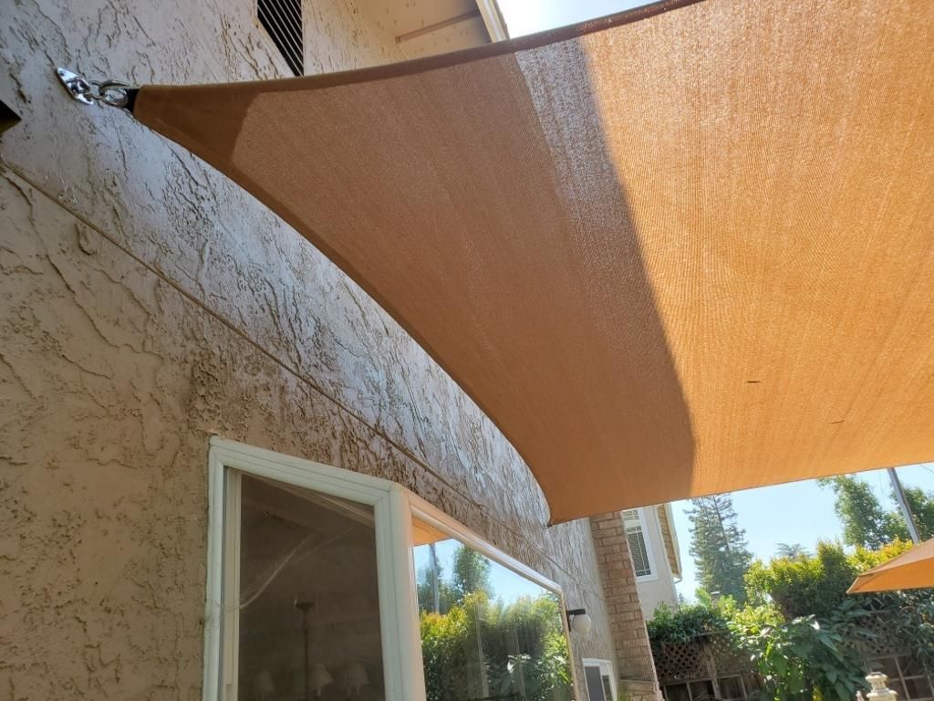 A large brown umbrella is hanging from the side of a building.