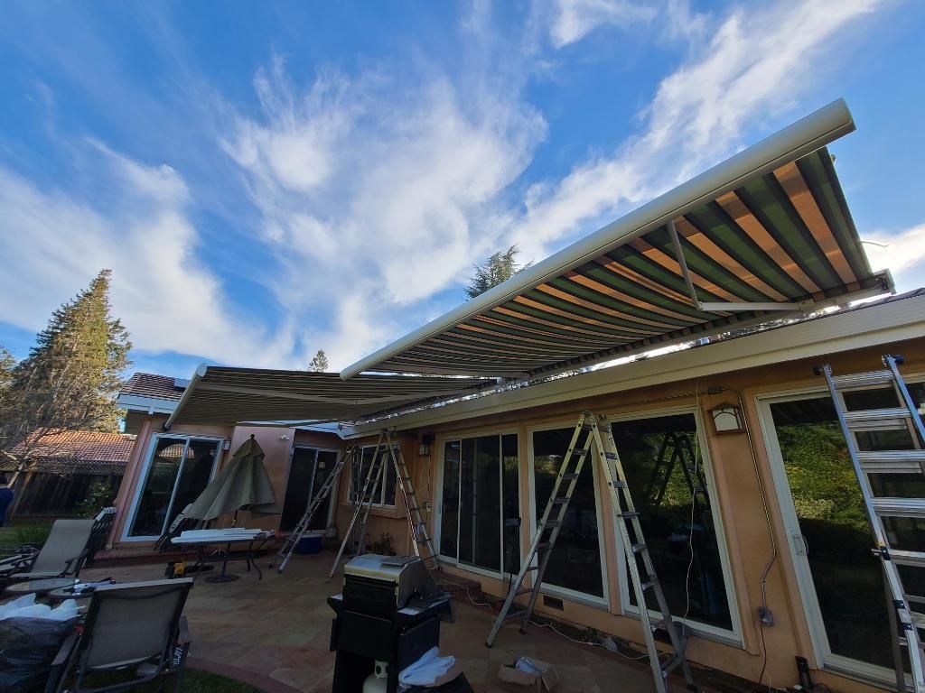 A large awning is being installed on the side of a house.
