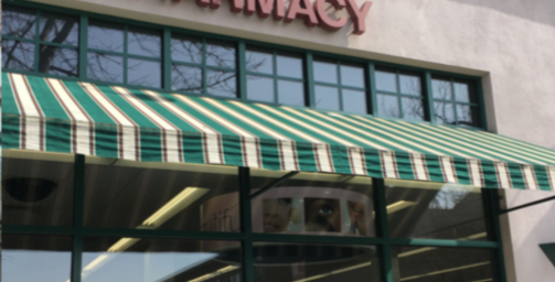 A green and white striped awning is on the front of a pharmacy