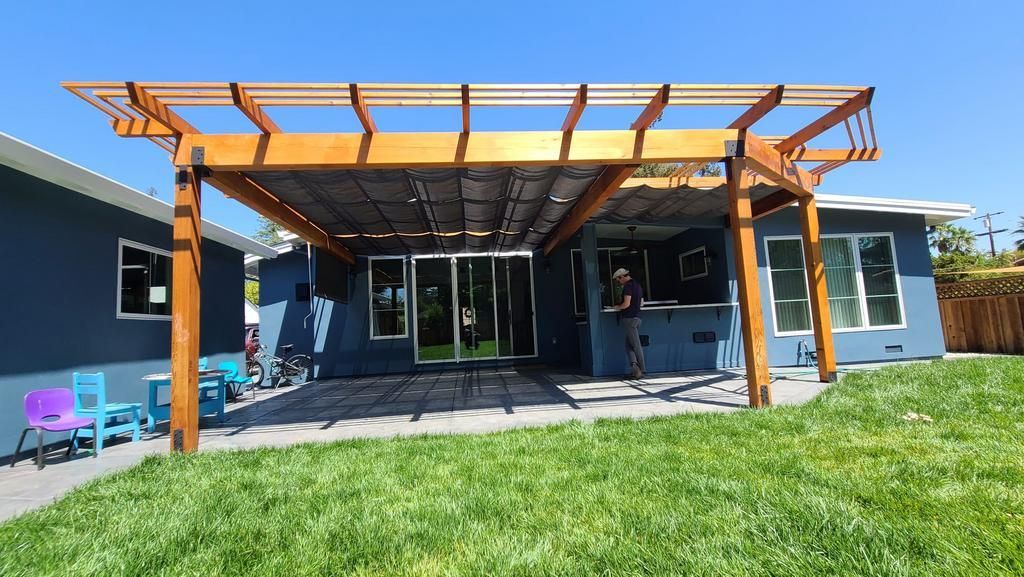 A house with a wooden pergola in the backyard.
