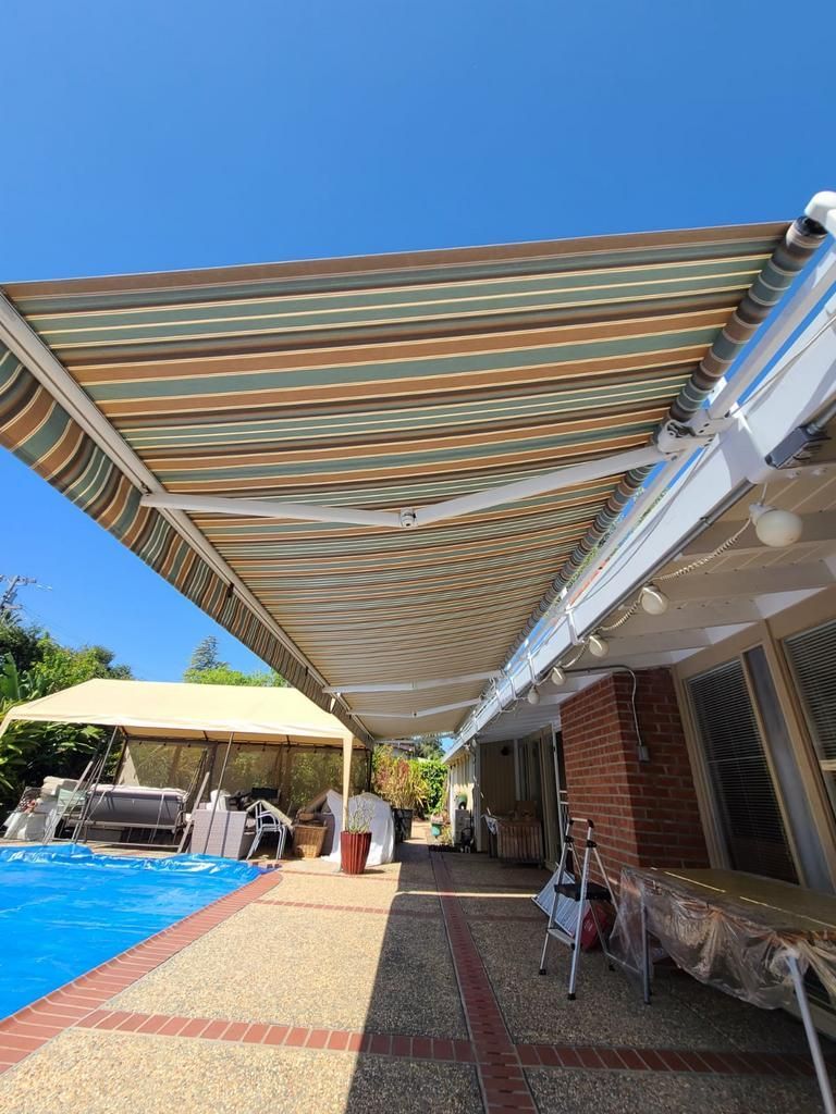 A large awning is over a swimming pool in a backyard.