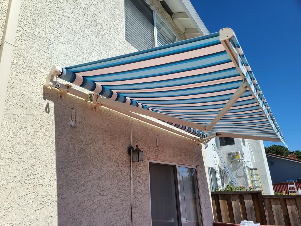 A blue and pink striped awning is on the side of a building.