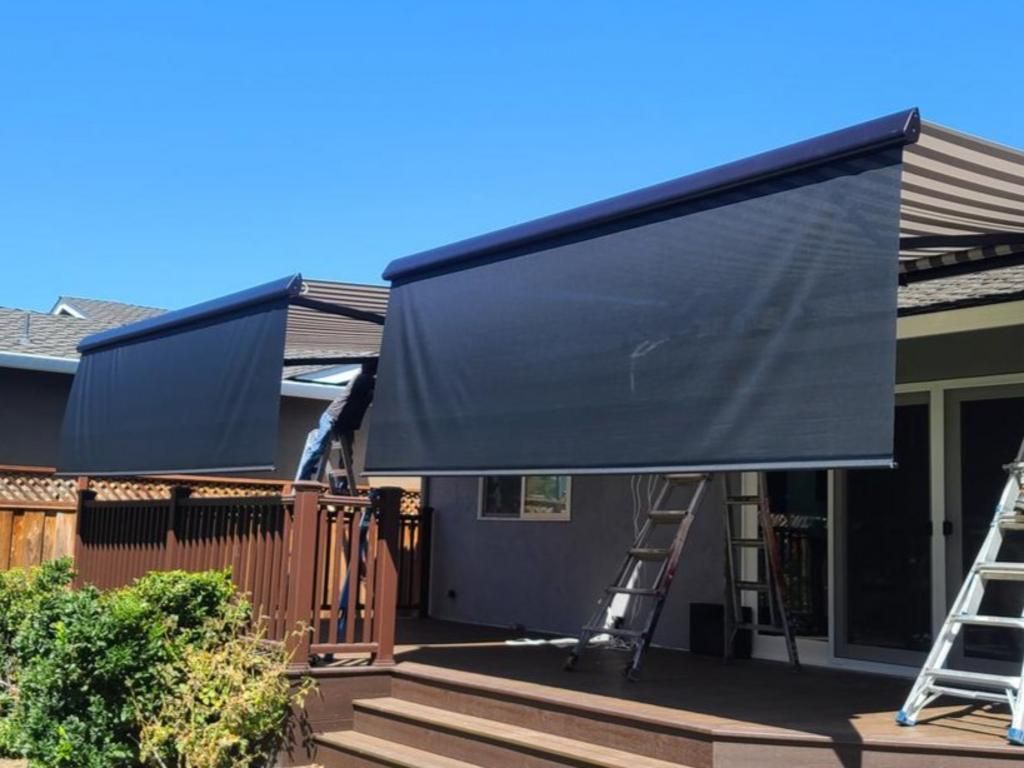 A black awning is being installed on the side of a house