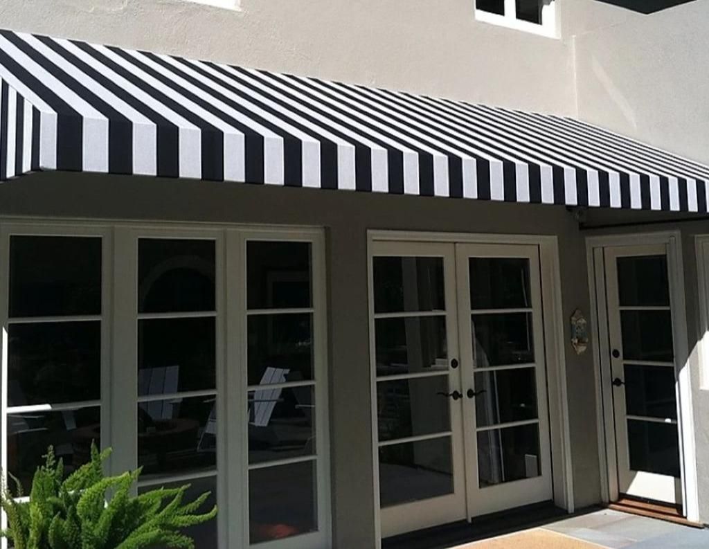 A black and white striped awning is on the side of a house