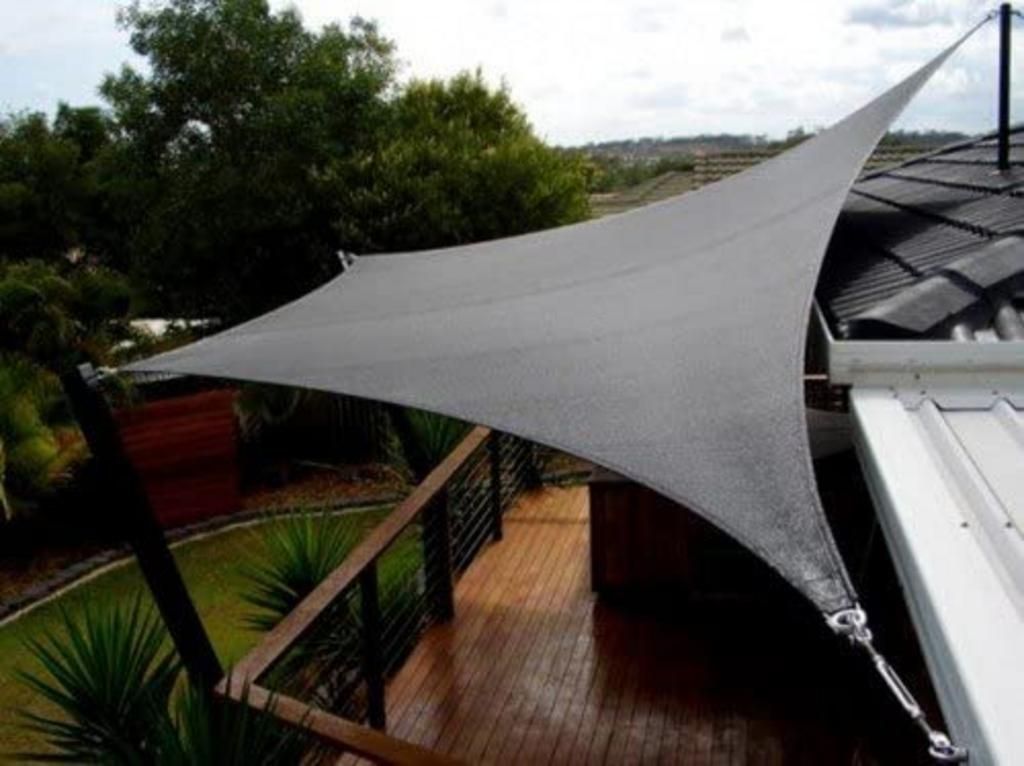 A gray shade sail is hanging over a wooden deck.