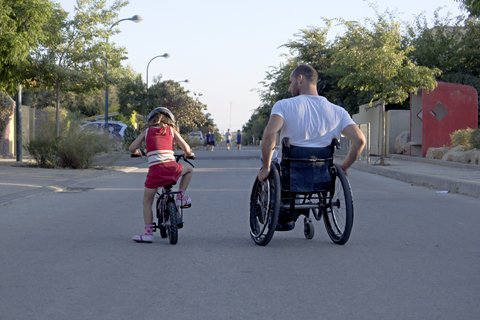 dad in wheelchair with daughter on bicycle