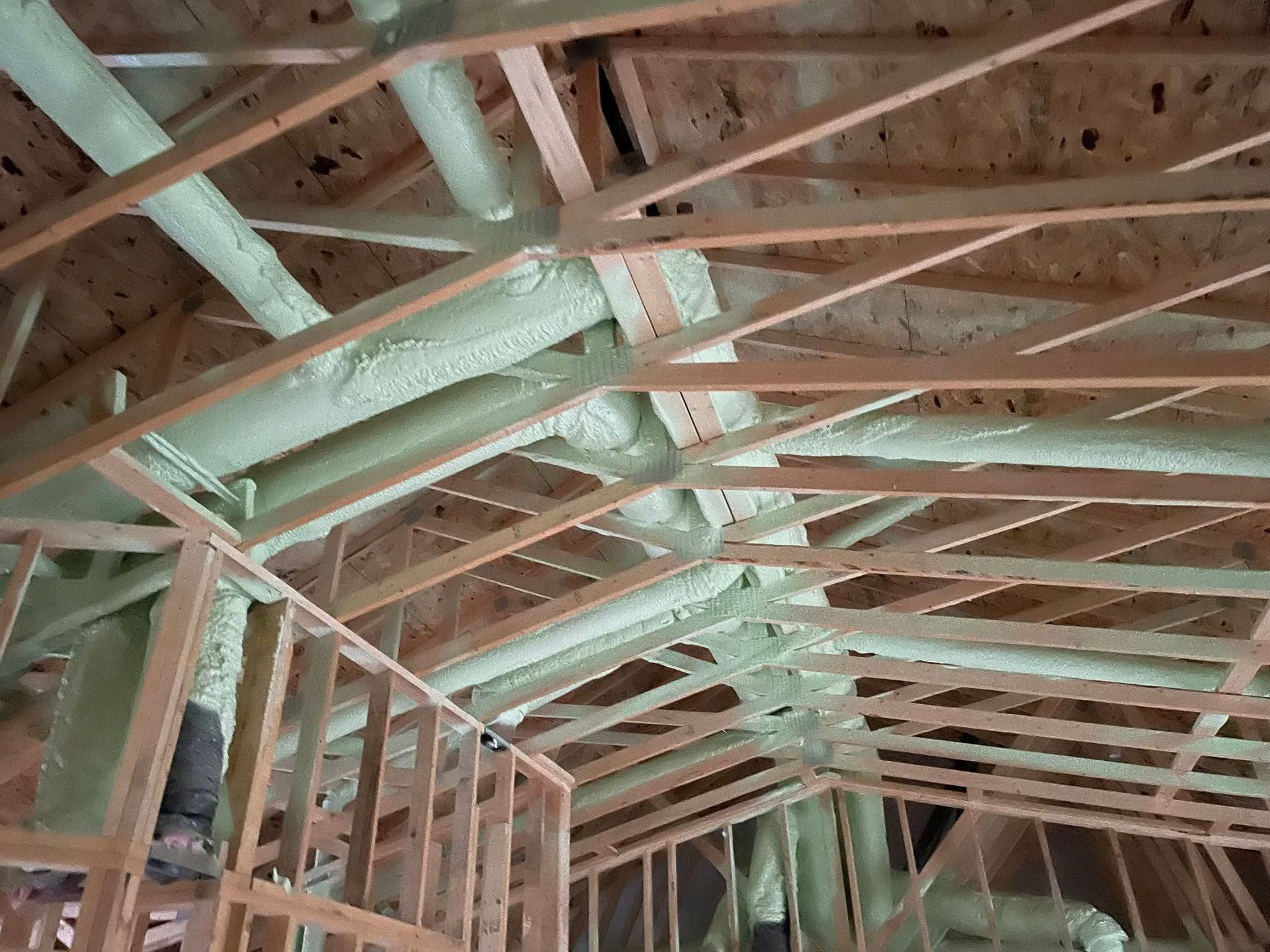 Wooden attic rafters with a large insulated duct running along the ceiling.