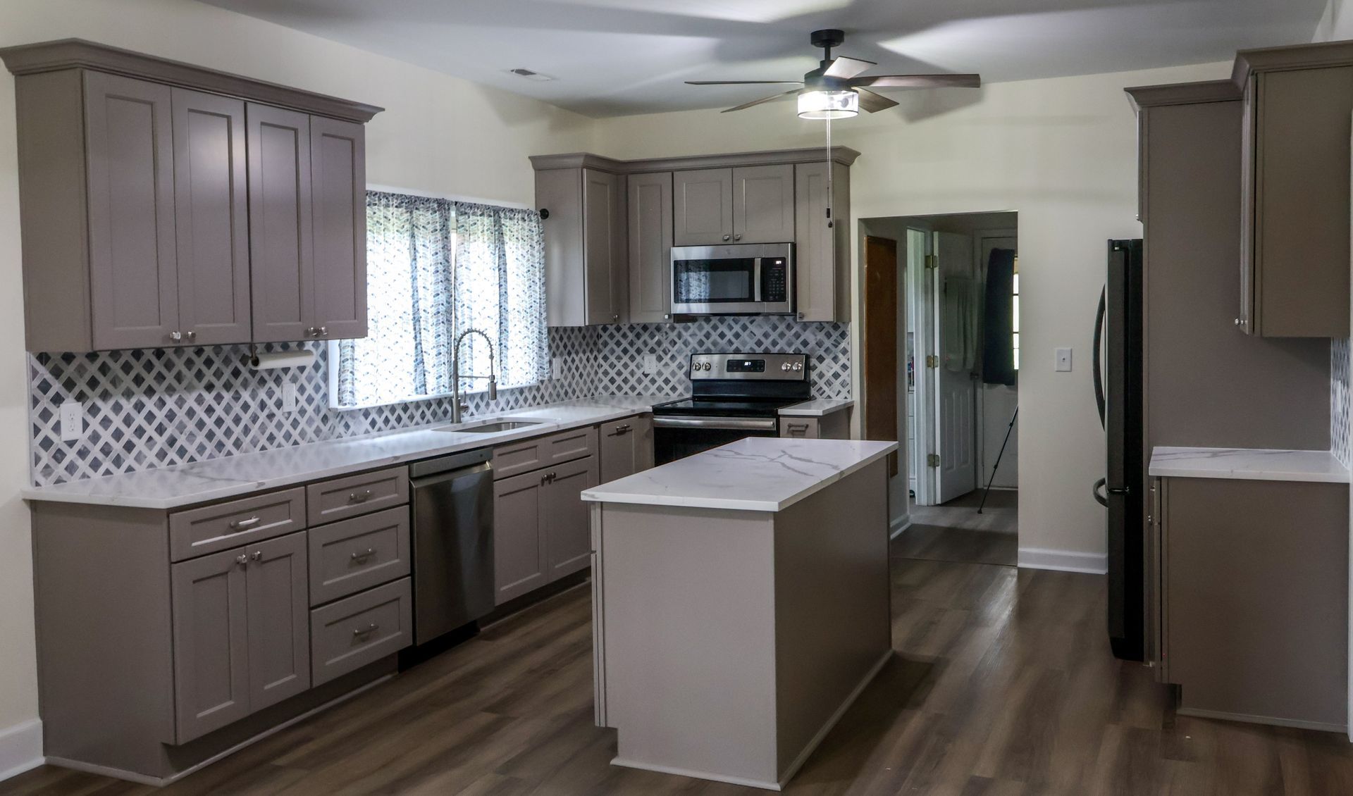 Gray kitchen with island, cabinets, stainless steel appliances, and white countertops.