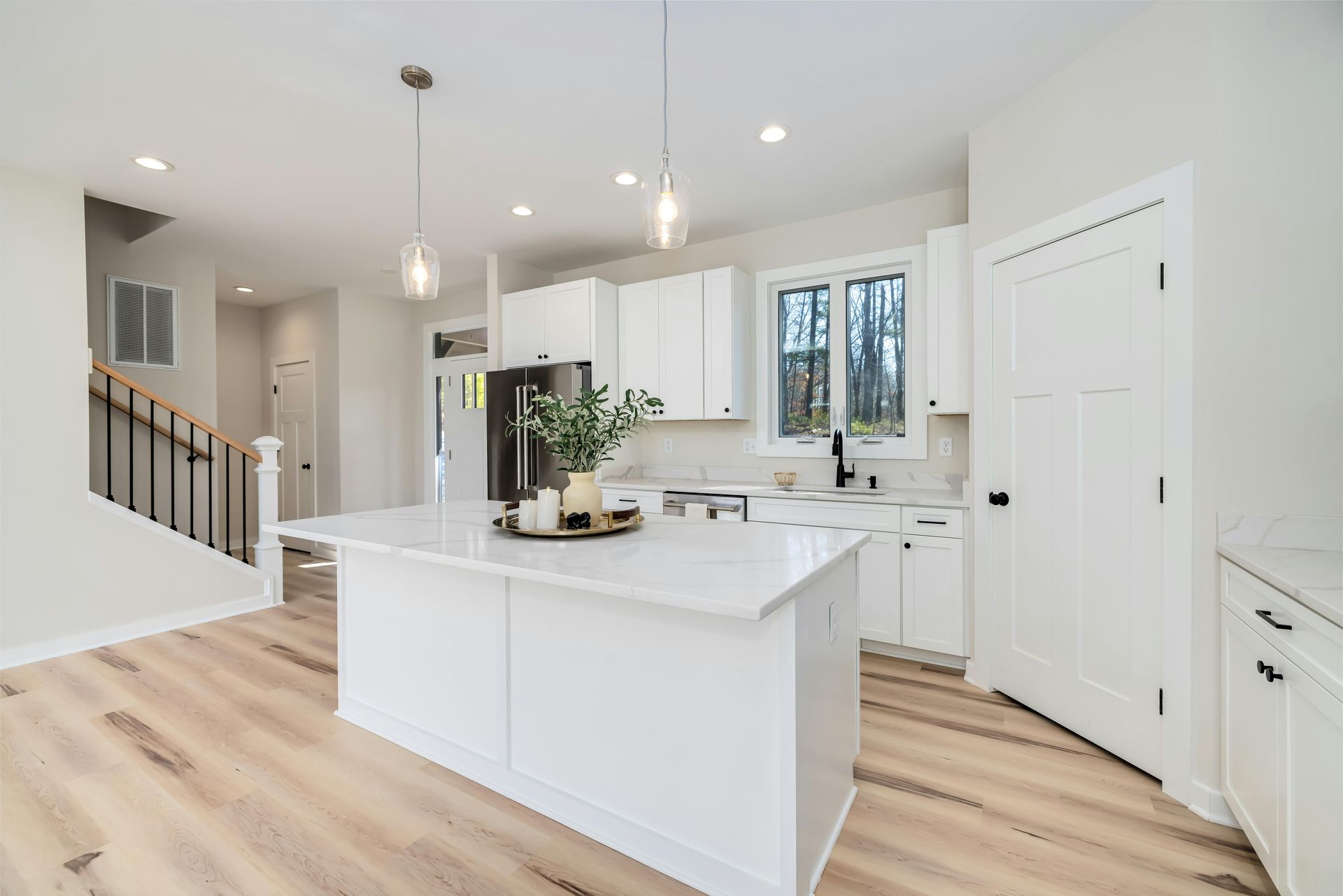 Bright white galley kitchen with wood floors, yellow walls, and a dining area at the back.