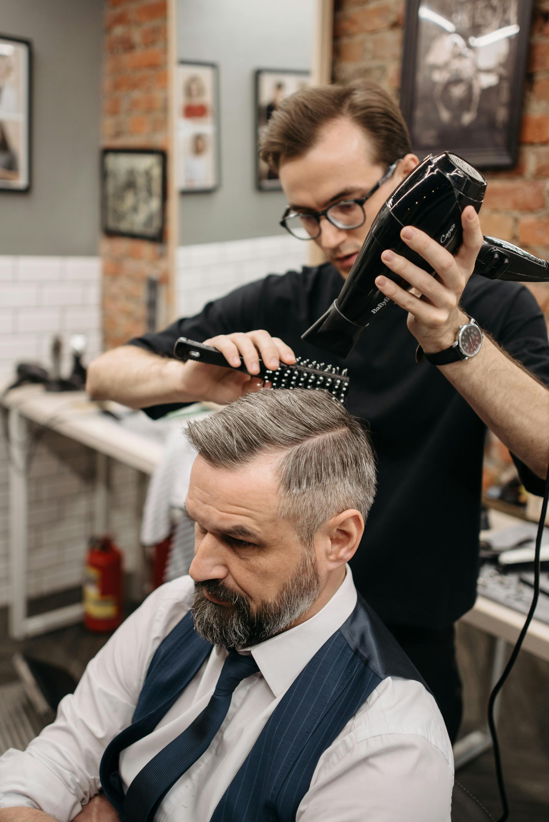 Hairdresser applying hairspray to a woman's updo in a salon.