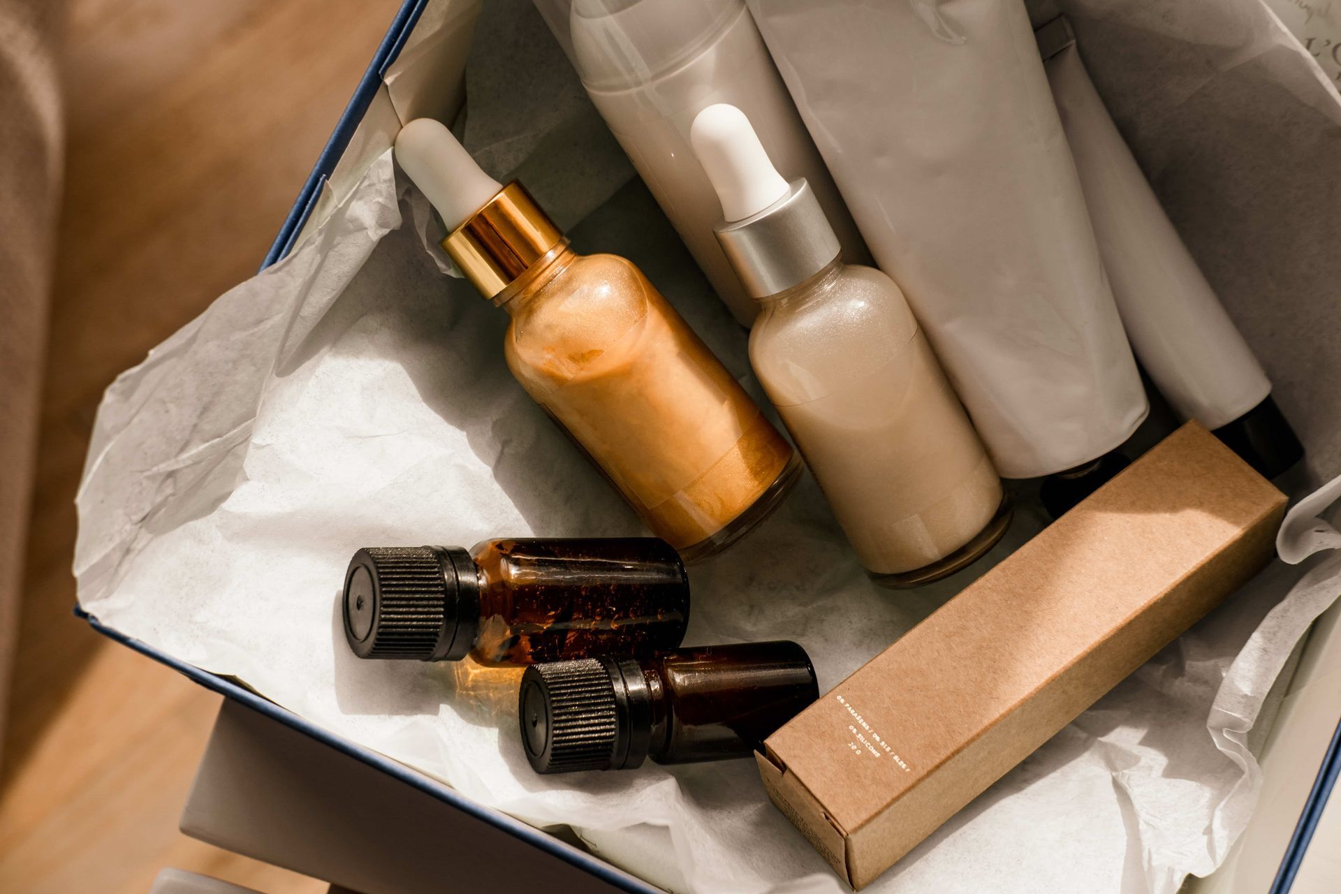 Skincare products in an open box lined with tissue paper; including dropper bottles and tubes.