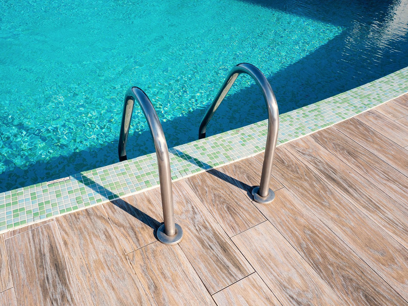 A swimming pool with a wooden deck and stairs leading to it.