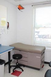 A doctor 's office with a stool , table , and window.