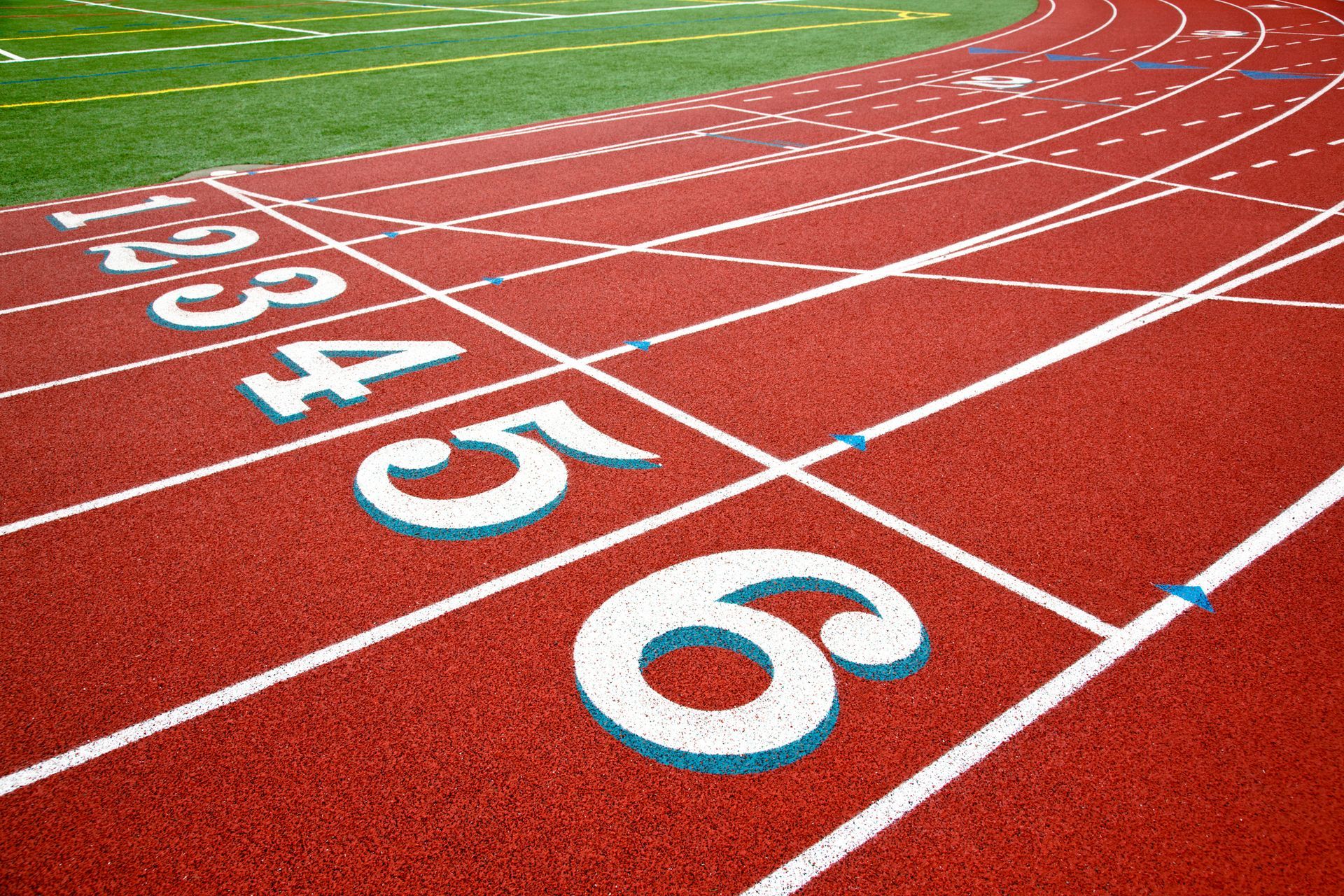 Running track with lanes numbered 1 through 6, red surface, green turf inside the track.