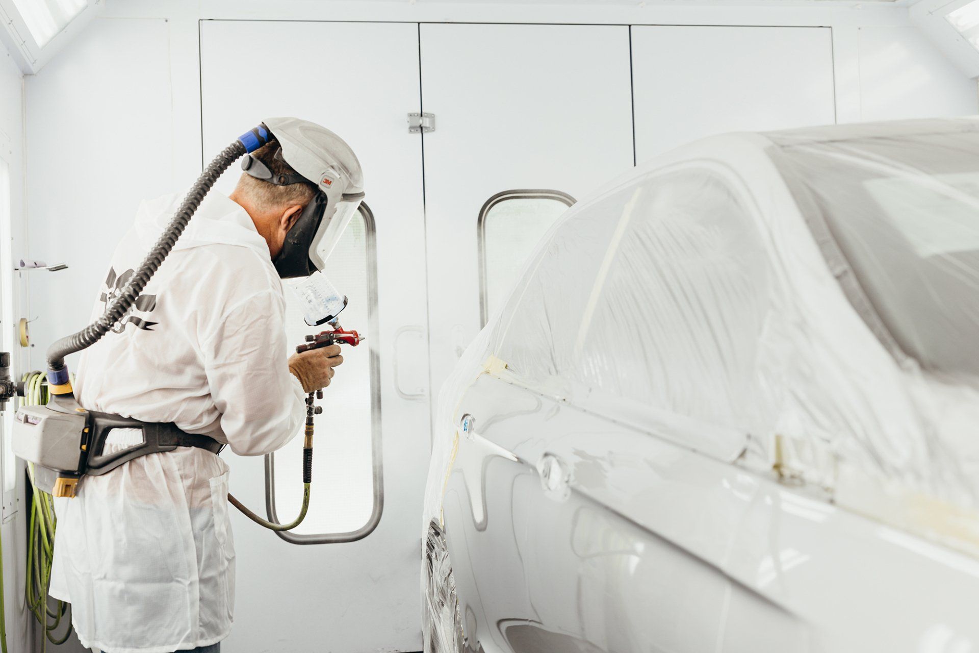 A Worker Spraying a Car With Paint. Trust Kemna Collision With Your Auto Body Repair in Mid-MO.