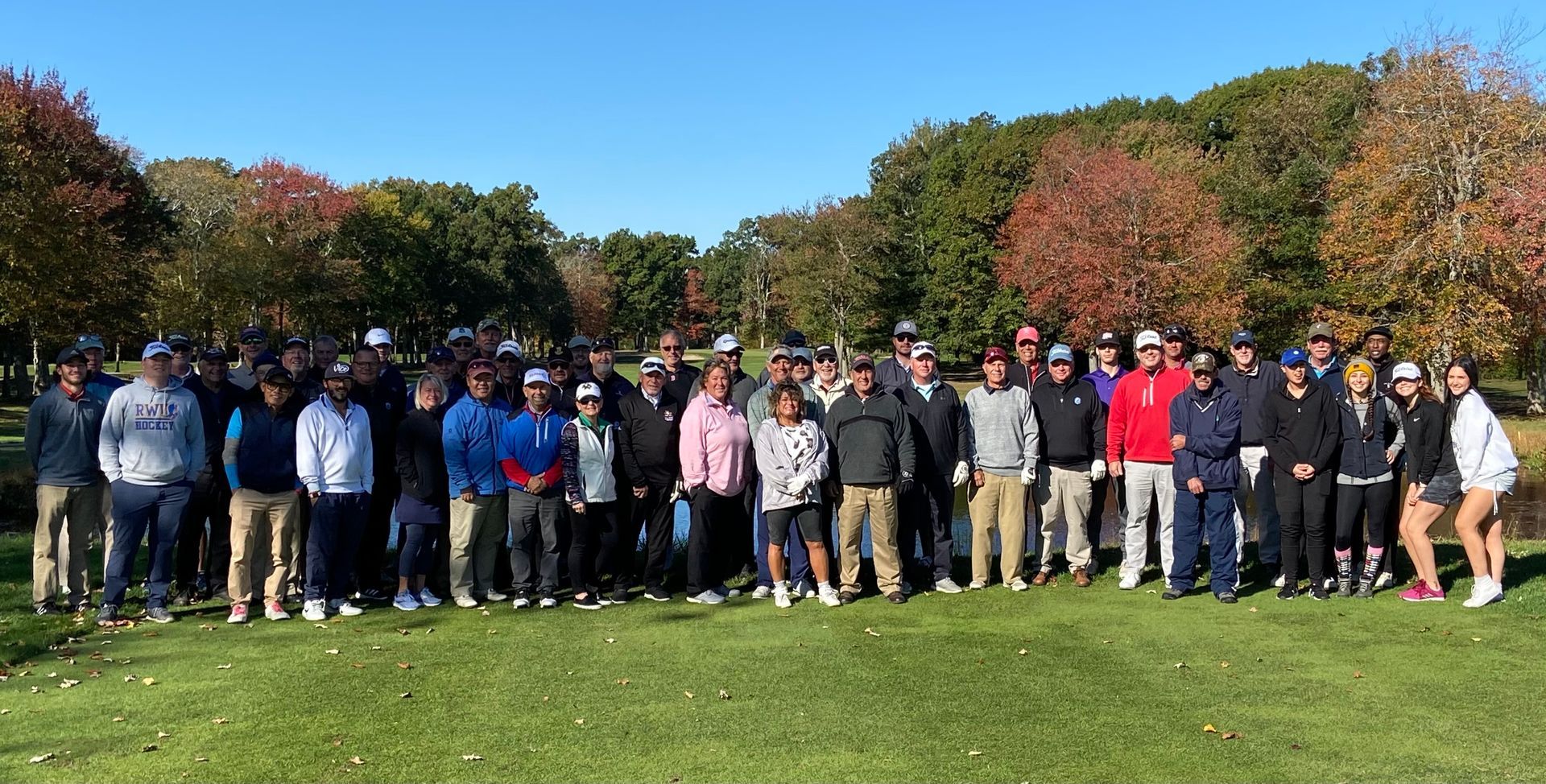 A large group of people are posing for a picture on a golf course.